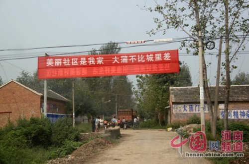 死者的家屬在村口迎接前來吊唁的親友，紅色的橫幅看上去更具諷刺意味。