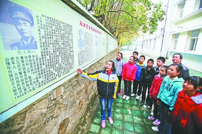 上圖：學校文化墻前，小講解員講述開國將軍杜義德的故事。記者何曉剛 攝