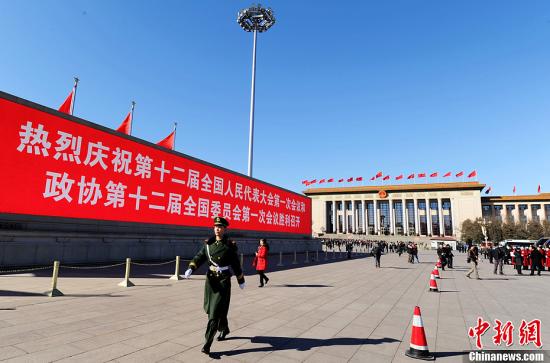 3月4日，北京晴空萬里，武警從北京天安門廣場大型顯示屏前走過。3月5日上午，十二屆全國人大一次會議將隆重開幕。中新社發 劉忠俊 攝